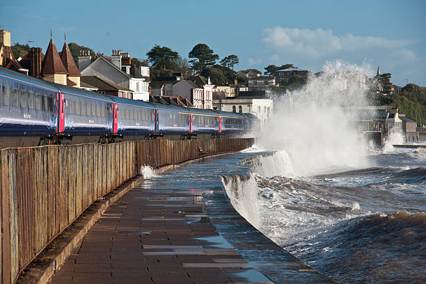 Train arriving at Dawlish with a wave breaking over it stock photo