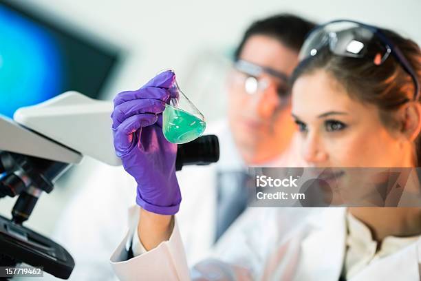 Cientistas A Olhar Para Um Balão Cónico De Solução De Cor - Fotografias de stock e mais imagens de Adulto