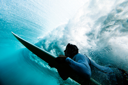 Surfer duck diving under reef break