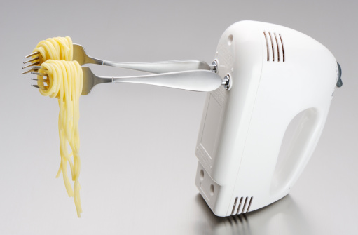 Electric mixer converted to a spaghettis rolling device with brushed silver forks instead of whips on a stainless steel background. (efficiency, ingeniuty or over eating concept). Note to inspector: only warning and caution written on mixer. More pictures of the same concept...