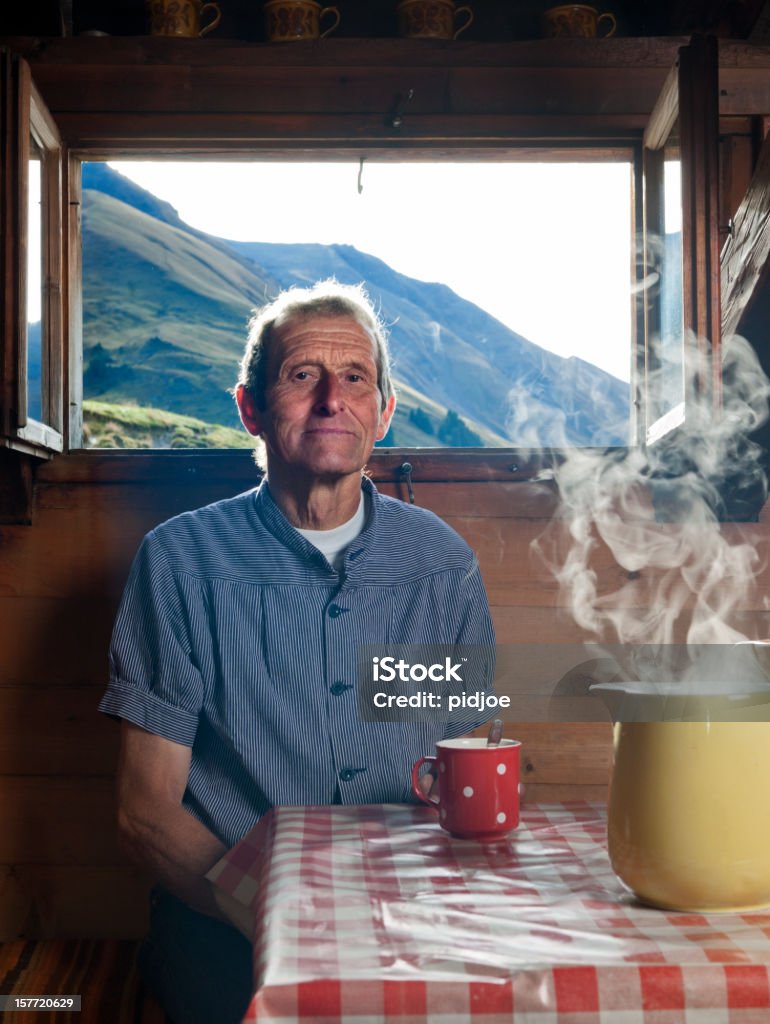 farmer having coffee break senior farmer sitting at table with steaming milk jug in front of open windows in farmhouse with view on the mountains drinking coffee, Lenklypse 2012 Farmer Stock Photo