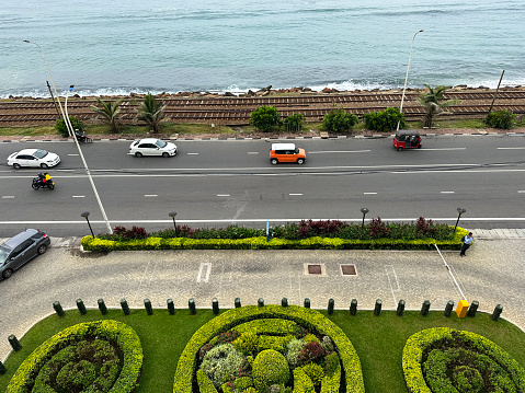 Colombo, Sri Lanka - January 17, 2023: Stock photo showing elevated view of Colombo seafront promenade with metal railway the line and gravel of southern line diesel railroad track running parallel to the coast with waves breaking on the rocky shore.