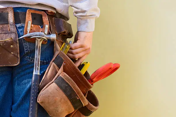 A young construction worker reaches into his tool belt.  Copy Space.