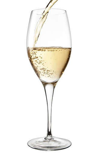 White wine being poured into a stemmed wine glass.