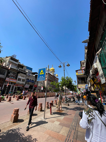 Chandni Chowk, Old Delhi, India - April 7, 2022: Stock photo showing queue of cycle rickshaw waiting on street in Chandni Chowk, Old Delhi, India with Gurudwara Sis Ganj Sahib a Sikh temple of worship in the distance.