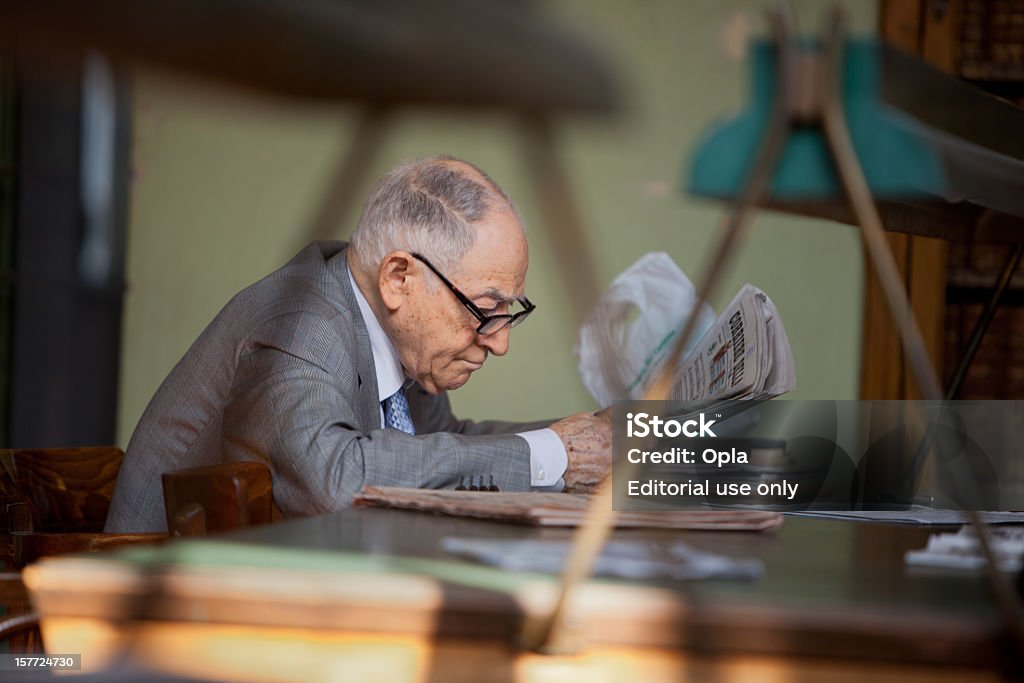 Senior hombre italiana de la lectura en la biblioteca pública - Foto de stock de 65-69 años libre de derechos