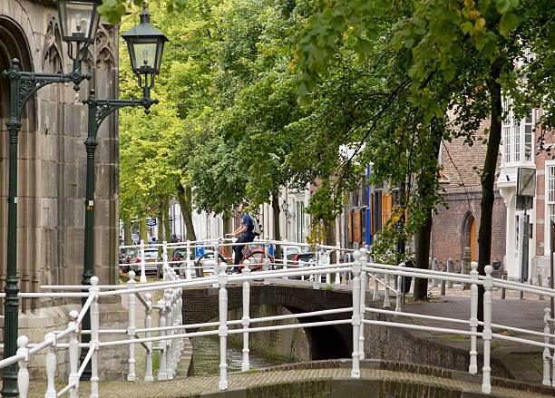 Delft, The Netherlands, August 27, 2025. Typical old town street view with canal water in the middle. Sunny summer day, wide angle view