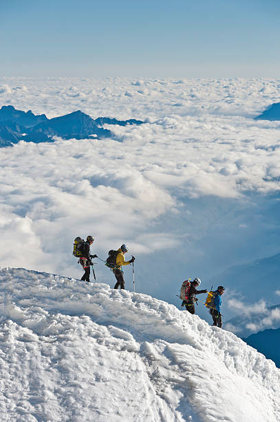 mountaineers escalada para baixo nevadascomment ridge acima de nuvens dos alpes - weather time travel locations nature imagens e fotografias de stock