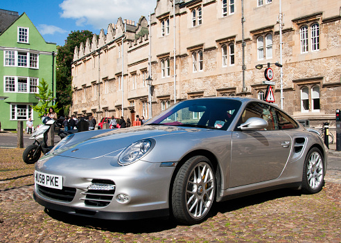 Oxford, England - May 8, 2011: Porsche 911 parked outside Oxford University building, students walking in the background and rear of Mercedes.