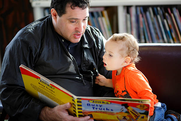 Father reading a book to his son stock photo