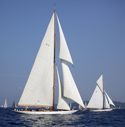 Imperia, Italy - September 10, 2023: Crew members aboard on sailboat Tuiga, flagship of the Monaco Yacht Club, during racing in Gulf of Imperia. Established in 1986, the Imperia Vintage Yacht Challenge Stage is a of the most important event in sailing the Mediterranean dedicated to historical boats