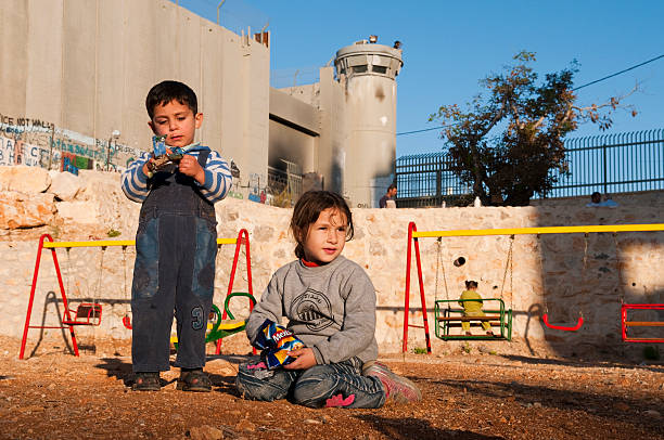 palestino crianças no playground ao lado de separação barreira parede em belém - muro da cisjordânia fotos - fotografias e filmes do acervo