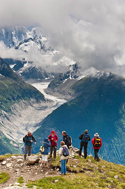 Woman hiker with backpack , helmet and rope hiking in the mountains, having Mont Blanc behind her