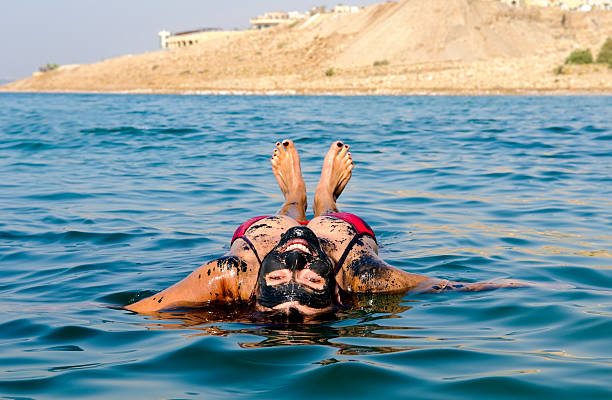A woman floating on her back in the Dead Sea after coating herself in mineral-rich mud