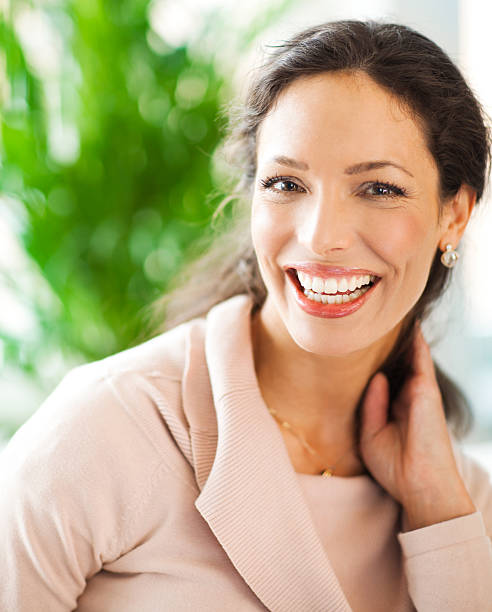 Woman holds her hair to her neck while smiling stock photo