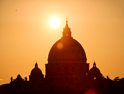 Vatican City, Vatican City State - September 23, 2011: The sun setting behind the huge dome of Saint Peter's Basilica.  The basilica is one of the world's most important Roman Catholic sites.