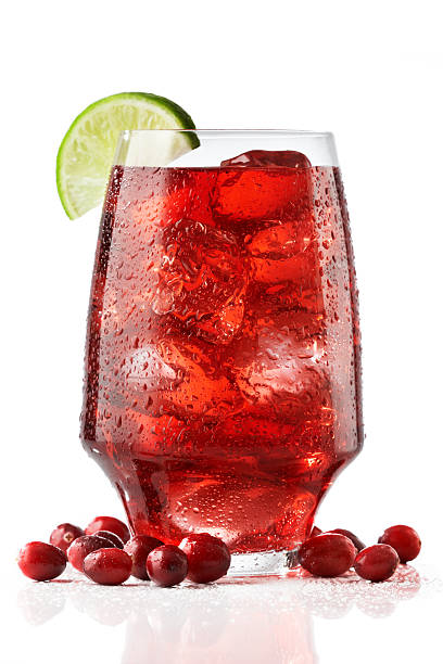 A wide tall glass of fresh cranberry juices served with lime stock photo
