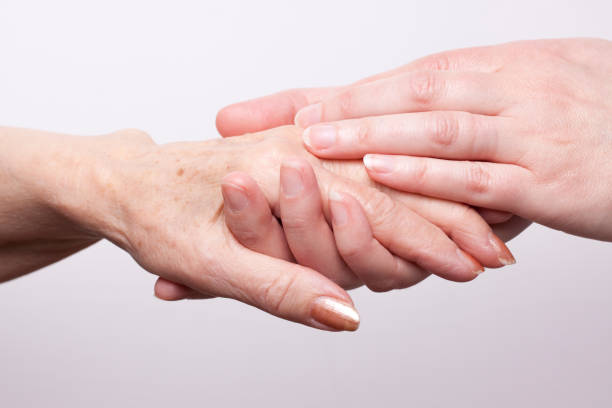 A set of younger hands holding the hand of an older woman stock photo