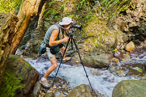 Photographer in a strange and uncomfortable position takes picture of Au Coin Falls with the tripod. Grenada W.I.