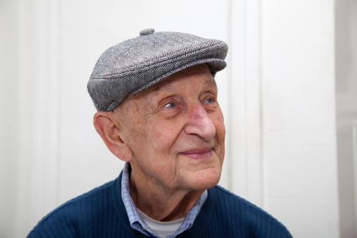 Senior man 90 years old smiling  with grey herringbone flat cap.