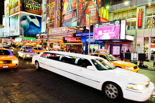 New York, United States - January 14, 2012: Limousine and people at Times Square at night.. At the junction of Broadway and the 7th avenue is brightly lit by neons and billboards and part of the theater district in Manhattan. It is also one of the main tourist attractions of the city.