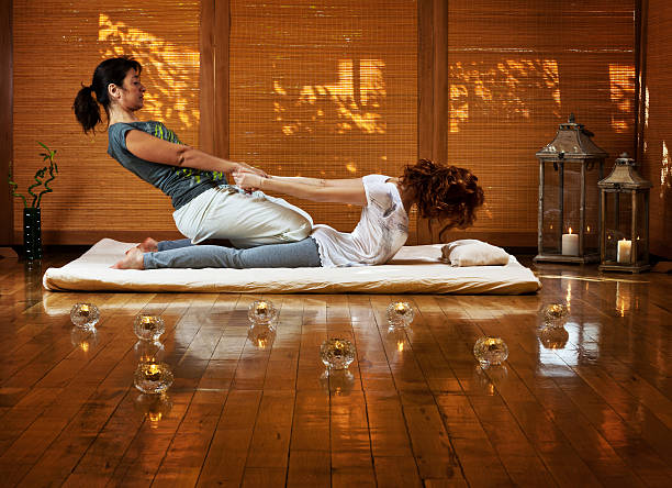 Thai massage Young female receiving massage by therapist in traditional thai position thai culture stock pictures, royalty-free photos & images