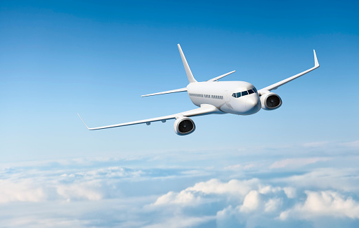 White business jet flies in the air above the clouds