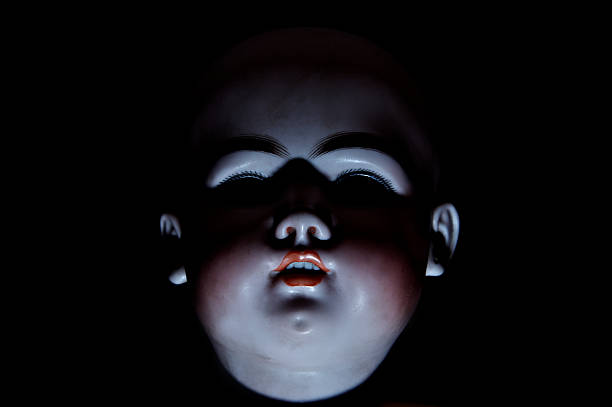 Sinister doll Isolated shadowy face of a vintage doll on black creepy doll stock pictures, royalty-free photos & images