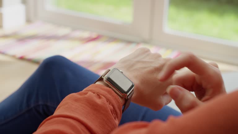 Unrecognizable woman checking messages on smartwatch at home relaxing on sofa