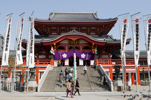 Miyajima, Japan - January 02, 2020: Local People and Tourists passing Wooden Bridge near the Temple Building in the Itsukushima street