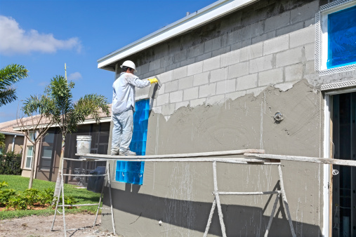 Real contractor Putting a base coat of stucco on a house