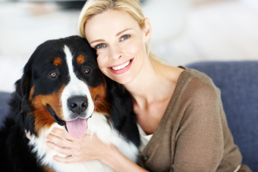 Beautiful woman hugging her adorable dog and smiling at you