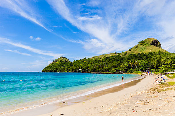 Pigeon Point Beach, Saint Lucia - November 29, 2011: tourists on the Pigeon Point Beach, at the foot of the Pigeon Island National Park visible on the background. This site was created after the 1970s, when the Pigeon Island and Saint Lucia were connected by a causeway where now luxury hotels are established.