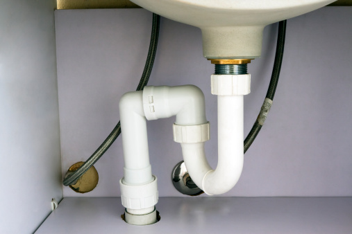 Under the bathroom sink pluming system in cabinet, full frame horizontal composition