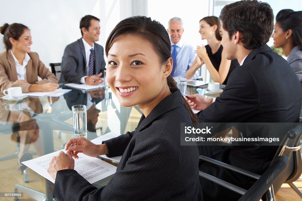 Asiática empresaria sentado en una mesa tipo sala de juntas - Foto de stock de 20 a 29 años libre de derechos