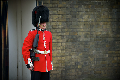 Windsor, United Kingdom - August 28, 2012: Afro-american Royal Guard with a rifle on duty near the back entrance of the Windsor Castle, one of the official residences of the British Royal Family located in a small town Windsor, Berkshire, England