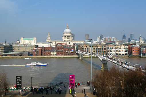 Boats on the Thames River with mixture of cranes, London skyline and the dome of Saint Paul's in the distance