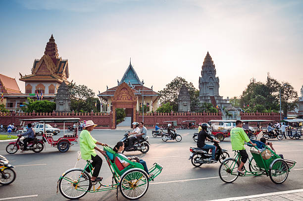belebten verkehr außerhalb wat ounalom bei sonnenuntergang in phnom penh - national landmark editorial color image horizontal stock-fotos und bilder