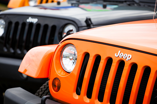 Halifax, Nova Scotia, Canada - May 13, 2012: Front fascia of two new Jeeps at a car dealership.  Vehicle in background is a Jeep Wrangler Sport and vehicle closest is a Jeep Wrangler Rubicon.  Focus in on Jeep logo on closest vehicle.  Along with the Wrangler, Jeep makes other models such as the Compass, Grand Cherokee, Patriot, and Liberty.