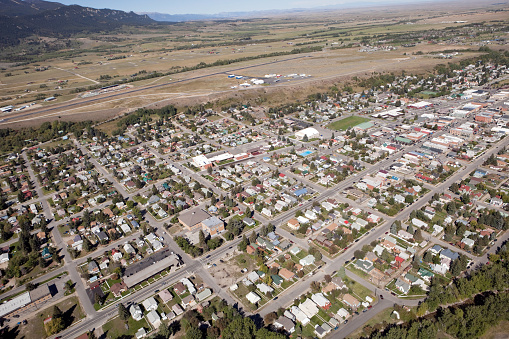 An aerial view of Red Lodge Montana, shot in September from a helicopter facing west. The main business district on Broadway is visible on the right, public pool in the middle and the airport and start of the Bear Tooth mountains are in the background.