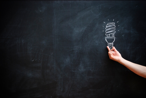 A hand seemingly holding a lightbulb which is drawn on a blackboard