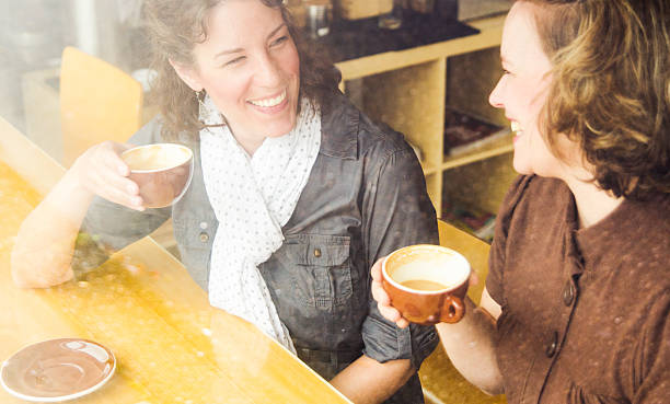 istock Two women in a coffee shop holding mugs while chatting 157733326