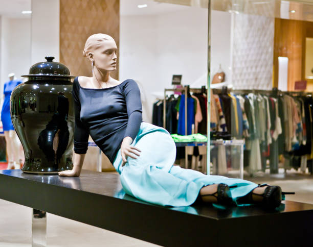 Elegant mannequin seated in a fashion-forward pose, surrounded by stacked gift boxes adorned with vibrant red ribbons. Soft lighting creates dramatic shadows, highlighting the mannequin's stylish attire and accessories.