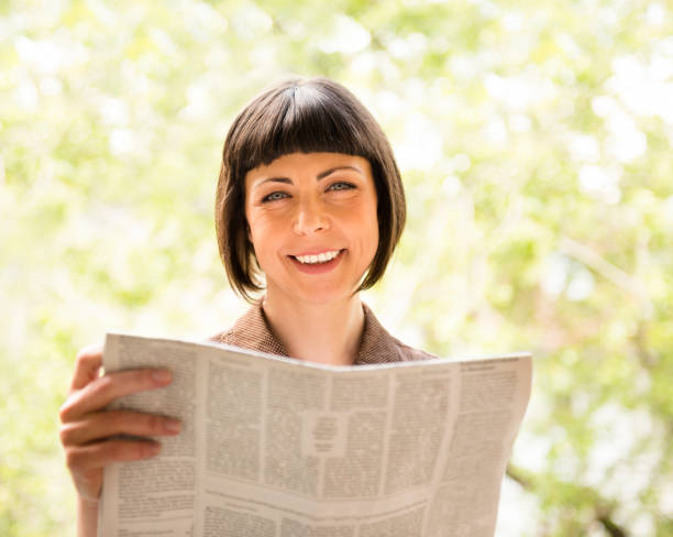 istock Smiling woman reading a newspaper 157733999