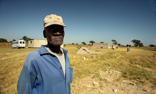 Low angle view of a happy old man holding his eyeglasses and looking away.