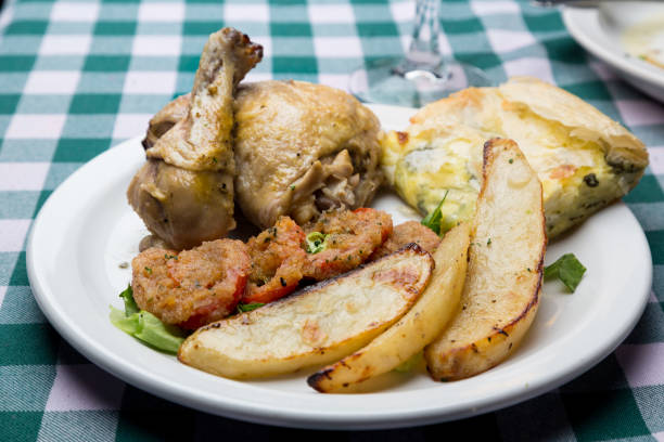 Authentic Greek Lemon Roasted Chicken Meal with roasted potato, spanikopita, grilled tomato and lemon and beer