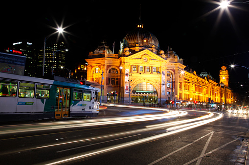 Pedestrians walk in front of Flinders Street Railway Station in Melbourne, Victoria, Australia on an overcast day.