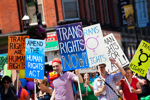 Halifax, Nova Scotia, Canada - July 28, 2012: Participants in the Halifax Pride Parade hold numerous signs as they walk down Barrington Street in the downtown district.  Signs include, \