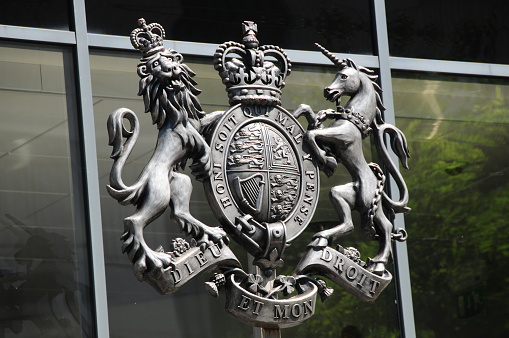 Castries, Saint Lucia: Coat of Arms of Saint Lucia on the stone façade of a government building. The government of Saint Lucia describes the arms as follows: Azure two sticks of cut bamboo in Cross surmounted of an African stool of authority Or between in dexter chief and sinister base a Rose Argent charged with another Gules both barbed and seeded proper an in sinister chief and dexter base a Fleur-de-lys Gold and for the Crest upon a Helm with a Wreath Or and Azure in front of two Fronds of the Fern Polypoduim in Saltire a Cubit Arm proper the hand holding erect a Torch Gold enflamed also proper and for the Supporters on either side a Saint Lucia Parrot commonly called Jacquot (Amazona versicolor) wings elevated and addorsed and in the beak of each a Frond of the Fern Polypoduim all proper and for the Motto: THE LAND-THE PEOPLE-THE LIGHT.