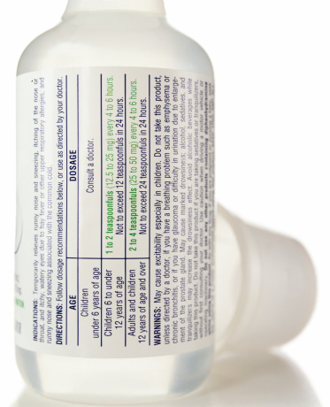 A bottle of over the counter medication Isolated on white focusing on the label with facts and warnings.